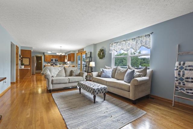 living room with a textured ceiling, light wood-type flooring, and a notable chandelier