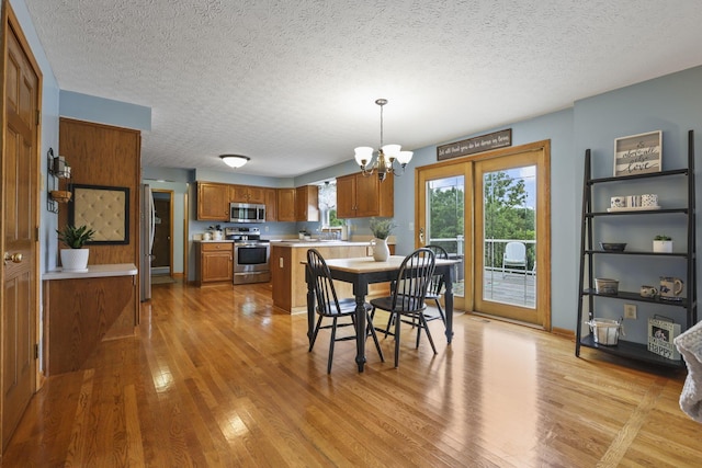 dining space with a textured ceiling, an inviting chandelier, and light hardwood / wood-style flooring