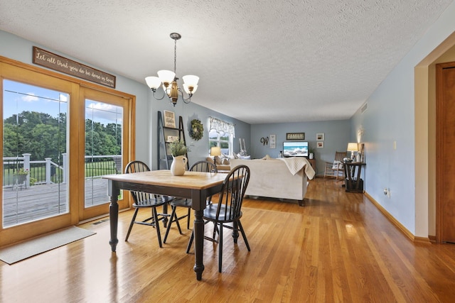 dining area with a chandelier, a textured ceiling, and light hardwood / wood-style floors