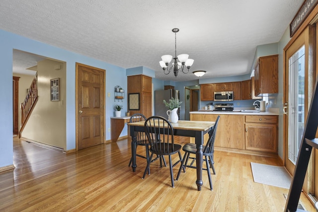 dining space featuring an inviting chandelier, sink, a textured ceiling, and light hardwood / wood-style flooring