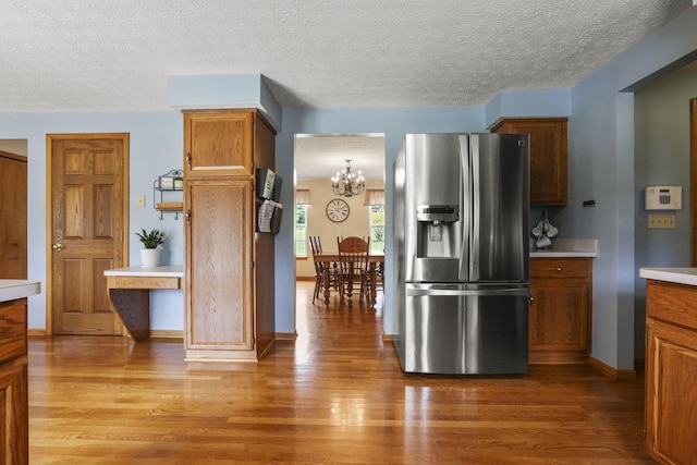 kitchen featuring a chandelier, stainless steel fridge with ice dispenser, light wood-type flooring, and a textured ceiling