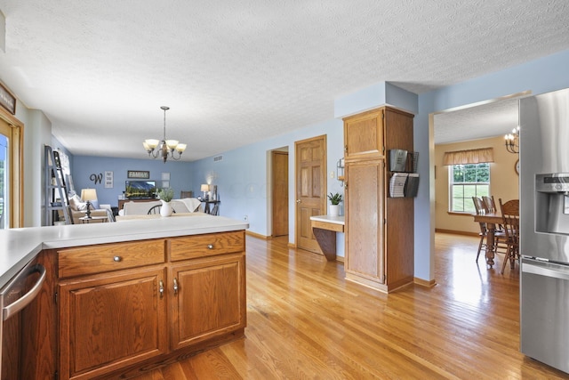 kitchen featuring a textured ceiling, stainless steel appliances, an inviting chandelier, light hardwood / wood-style flooring, and hanging light fixtures