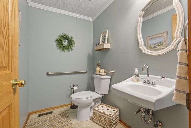 bathroom with sink, tile patterned flooring, toilet, ornamental molding, and a textured ceiling