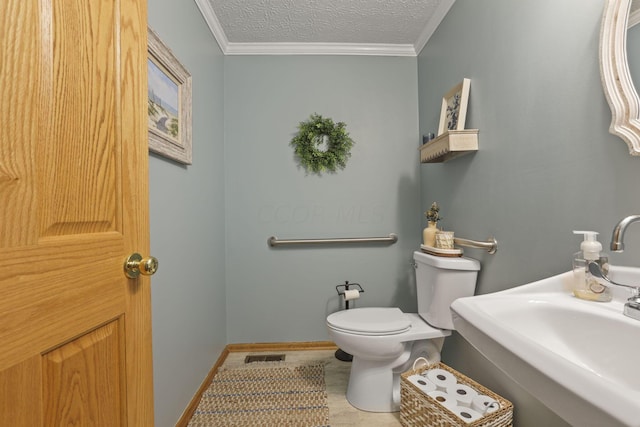 bathroom featuring tile patterned floors, ornamental molding, a textured ceiling, sink, and toilet