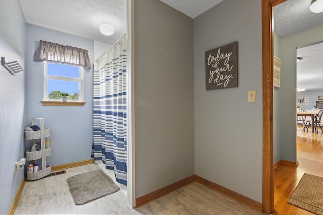 bathroom featuring a shower with shower curtain, hardwood / wood-style floors, and a textured ceiling