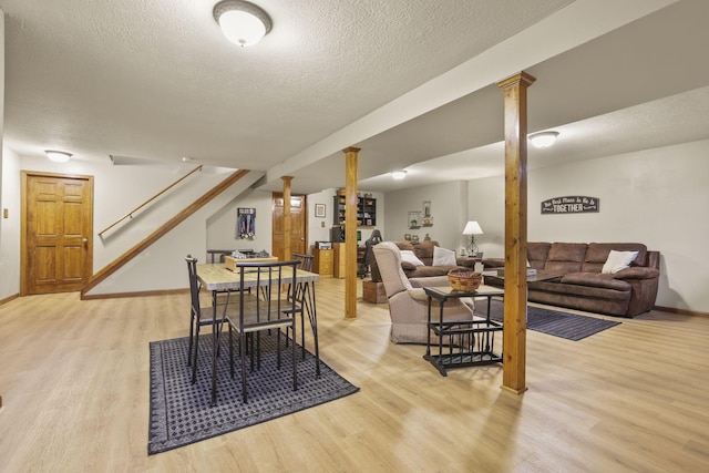 dining area with ornate columns, light hardwood / wood-style floors, and a textured ceiling