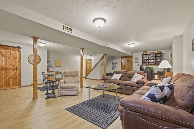 living room with a barn door, light wood-type flooring, and a textured ceiling