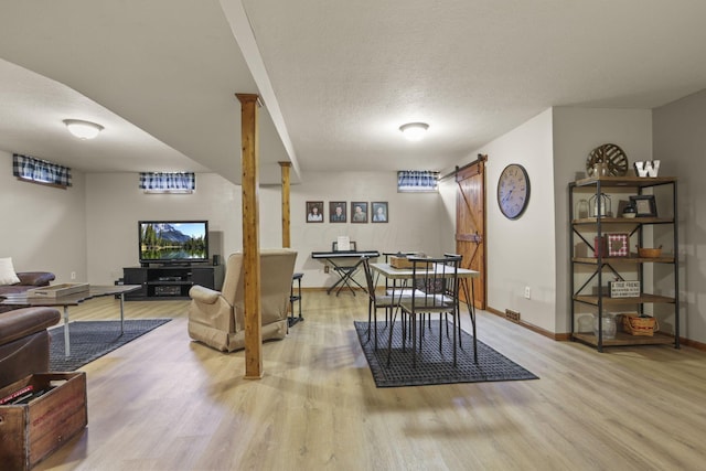 dining room with a textured ceiling, a barn door, and light hardwood / wood-style floors