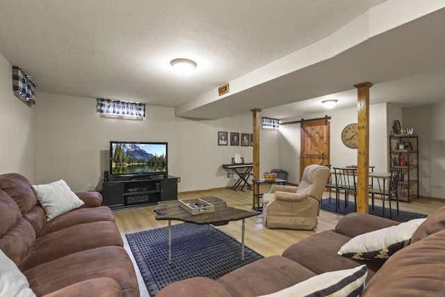 living room with light hardwood / wood-style floors, a barn door, and a textured ceiling