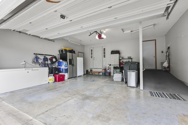 garage with stainless steel fridge and a garage door opener