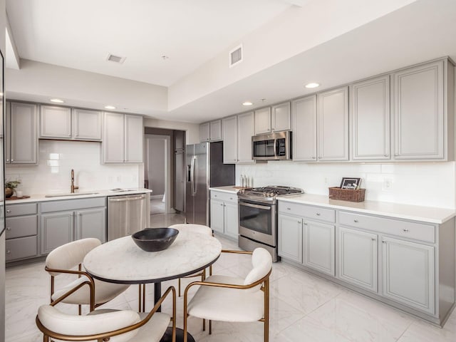 50 W Broad St Unit 2905, Columbus, OH 43215 - kitchen featuring stainless steel appliances, gray cabinets, light marble finish floors, decorative backsplash, and recessed lighting