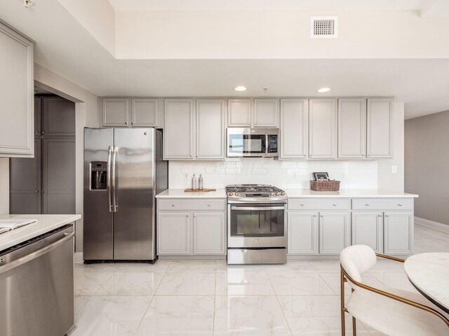 50 W Broad St Unit 2905, Columbus, OH 43215 - kitchen featuring appliances with stainless steel finishes, light marble finish floors, light countertops, tasteful backsplash, and recessed lighting