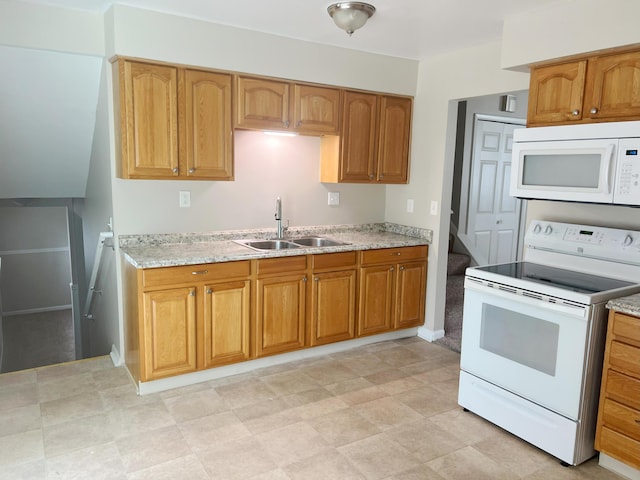 kitchen featuring light stone countertops, white appliances, and sink