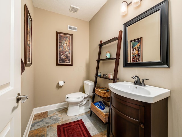 bathroom with toilet, a textured ceiling, and vanity