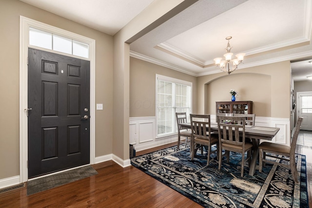 entrance foyer featuring a raised ceiling, a chandelier, ornamental molding, and a healthy amount of sunlight