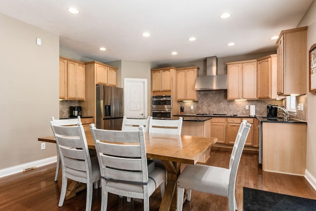 kitchen featuring light brown cabinets, appliances with stainless steel finishes, dark hardwood / wood-style flooring, a kitchen island, and wall chimney exhaust hood