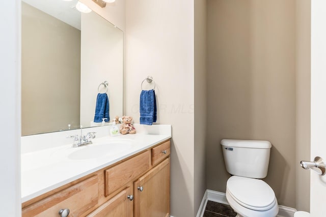 bathroom with toilet, vanity, and tile patterned flooring