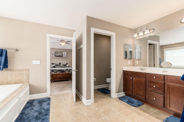 bathroom with tile patterned flooring, a tub, toilet, vanity, and ceiling fan