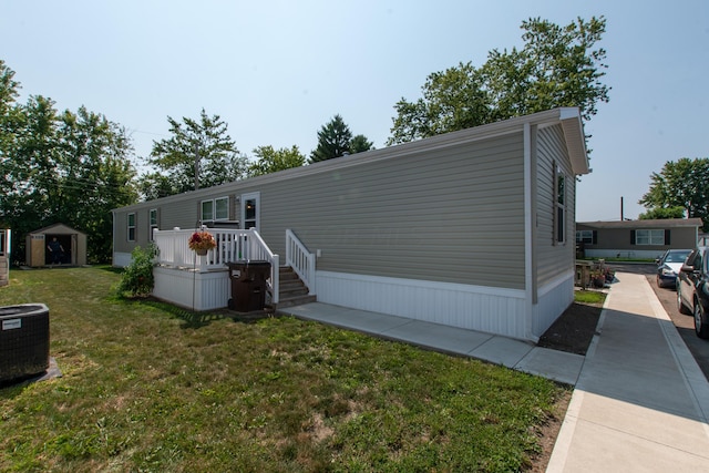 manufactured / mobile home featuring central AC, a front lawn, and a storage shed