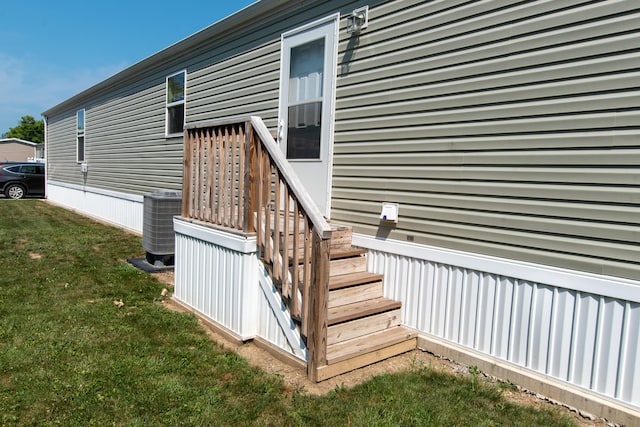 entrance to property featuring a yard and central AC unit