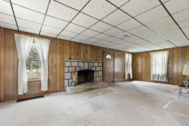 unfurnished living room with wood walls, light colored carpet, and a fireplace