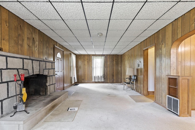 interior space with wooden walls, a fireplace, and light carpet