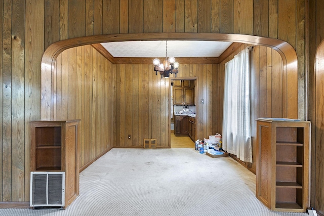 interior space with a notable chandelier, wood walls, and light carpet