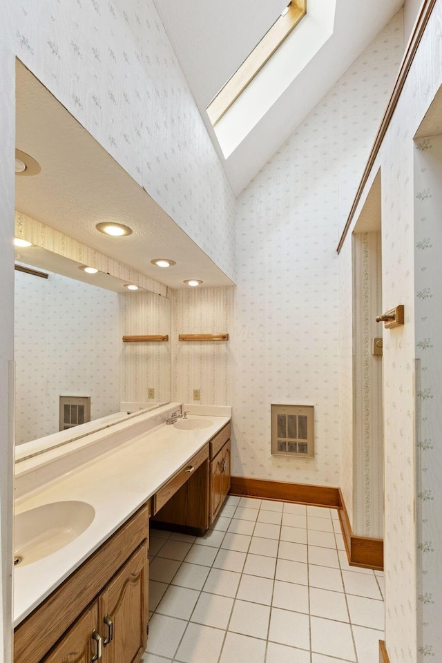 bathroom with tile patterned floors, vanity, and lofted ceiling with skylight