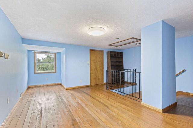 empty room with hardwood / wood-style floors and a textured ceiling