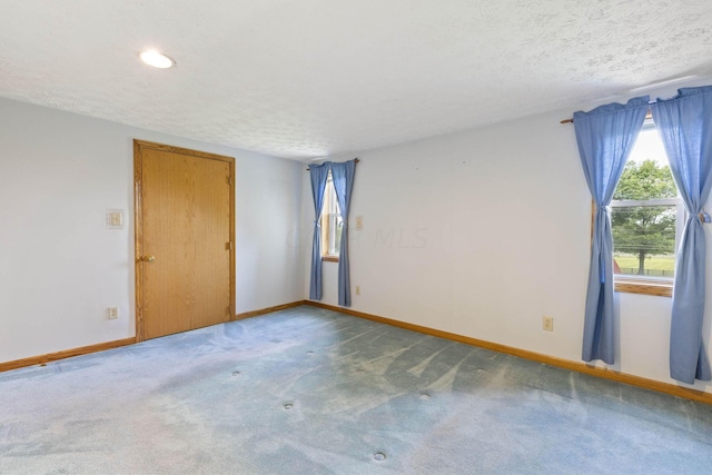 carpeted spare room with a textured ceiling