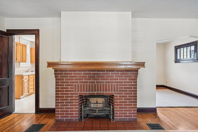 interior details featuring tasteful backsplash, sink, wood-type flooring, and a brick fireplace