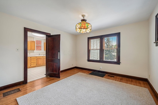 unfurnished room with sink and light hardwood / wood-style flooring