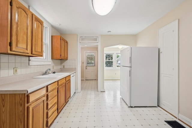 kitchen with backsplash, sink, and white appliances