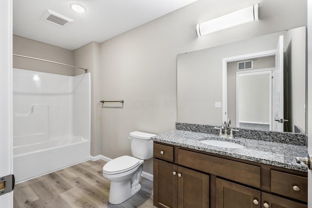 full bathroom with hardwood / wood-style floors, vanity, bathing tub / shower combination, and toilet