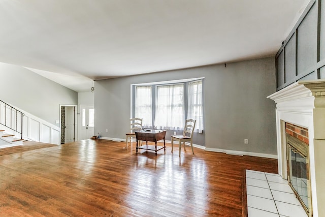 living room with light hardwood / wood-style floors, vaulted ceiling, and a brick fireplace