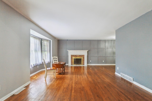 unfurnished living room featuring wood-type flooring and a brick fireplace