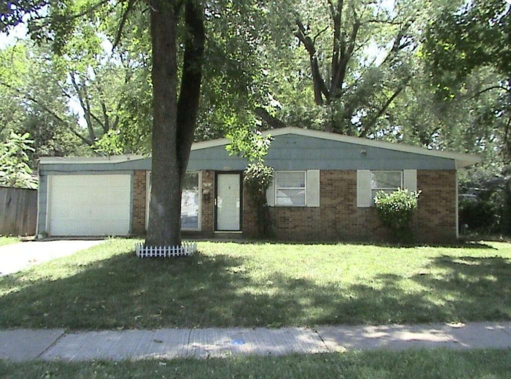 ranch-style house featuring a garage and a front lawn