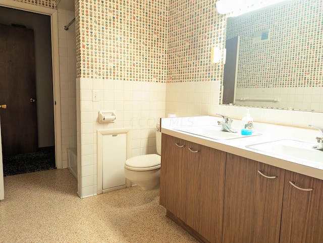 bathroom featuring vanity, toilet, and tile walls