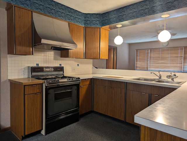 kitchen with pendant lighting, backsplash, black stove, sink, and wall chimney exhaust hood