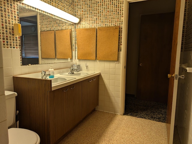 bathroom with vanity, toilet, and tile walls