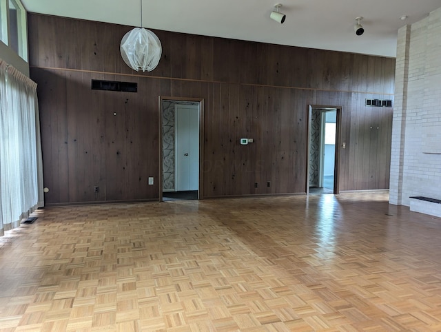 empty room with a towering ceiling, wooden walls, and light parquet flooring