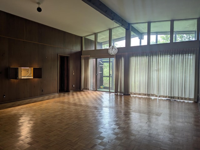 unfurnished living room featuring beam ceiling, parquet floors, wood walls, and high vaulted ceiling