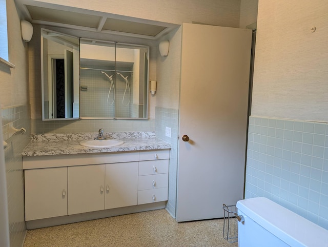 bathroom featuring vanity, toilet, and tile walls