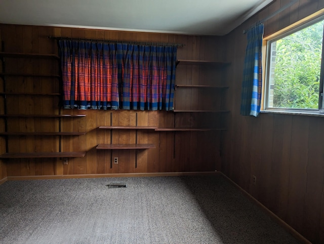 carpeted spare room featuring wood walls