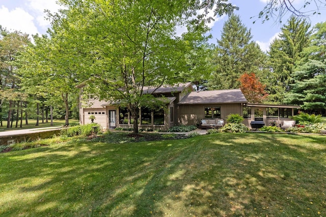 rear view of property featuring a garage and a lawn