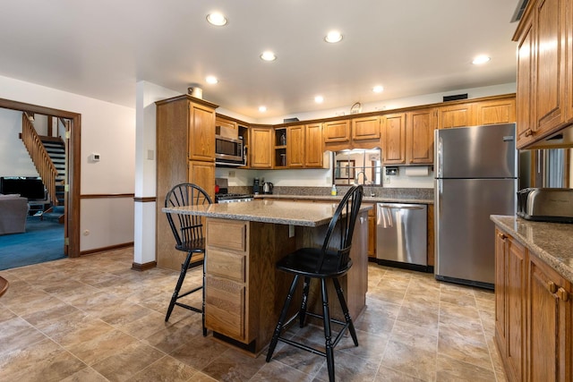 kitchen featuring a breakfast bar area, stone counters, a kitchen island, and stainless steel appliances