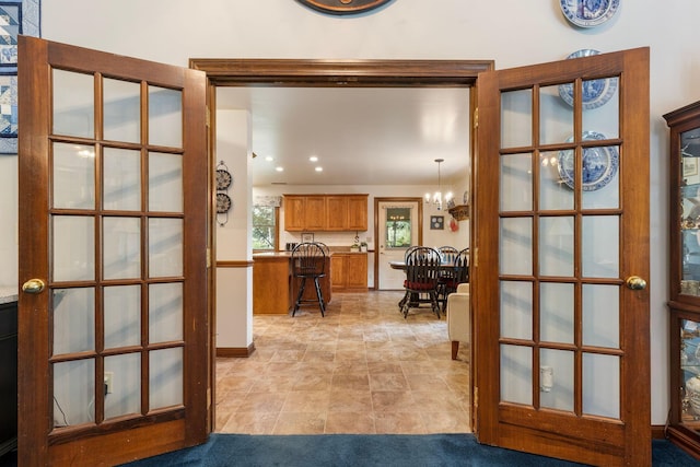 corridor featuring french doors and a notable chandelier