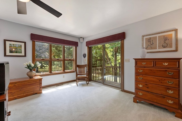 living area with light carpet and ceiling fan