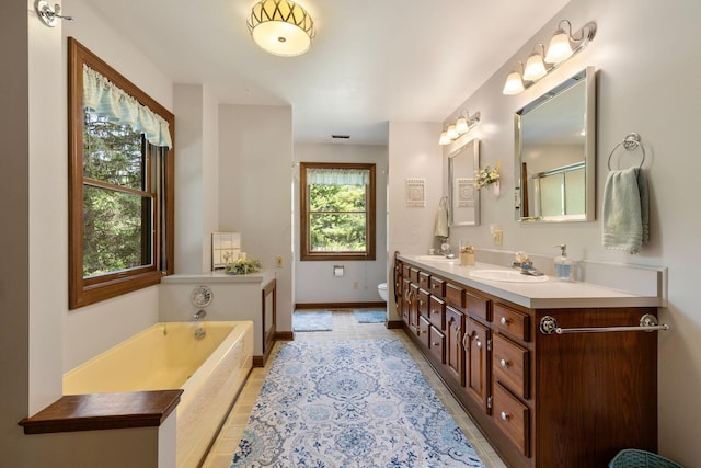 bathroom with vanity, a relaxing tiled tub, and toilet