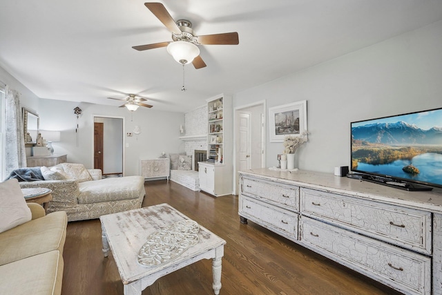 living room featuring a brick fireplace, ceiling fan, and dark wood-type flooring